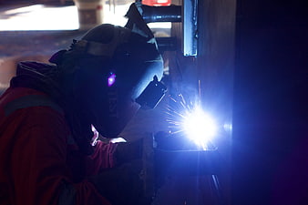Industrial Welder Working With Bright Sparks In Dark Factory