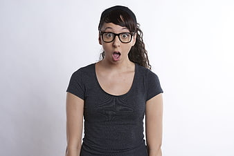 Surprised young woman with glasses and headband on white background