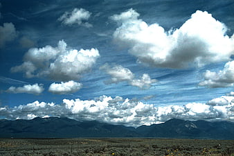 Vast desert landscape with dramatic clouds and distant mountains