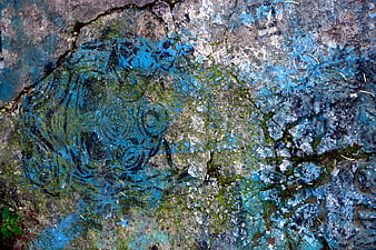 Weathered blue graffiti flowers on cracked concrete sidewalk