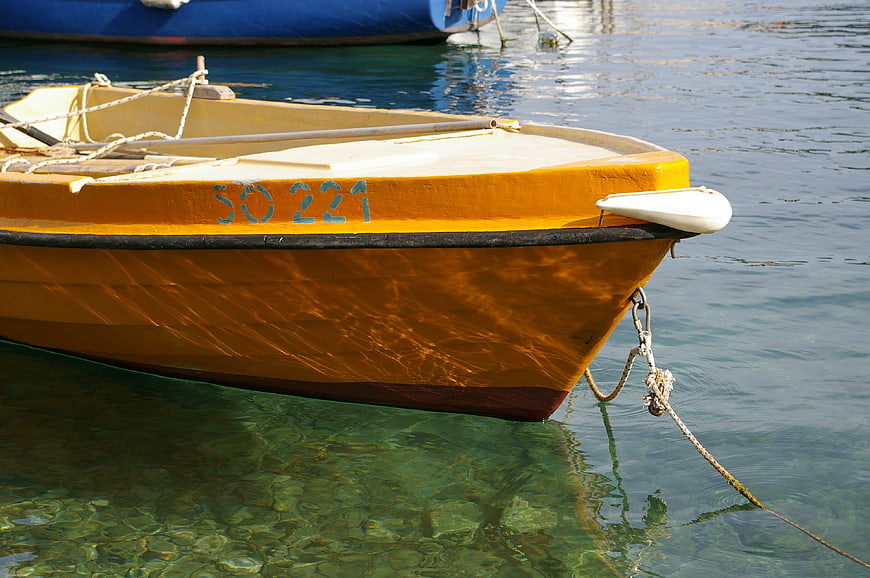 Yellow wooden boat floating in clear turquoise water