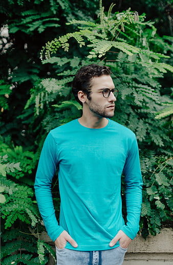 Man in Turquoise Shirt Standing Against Green Foliage
