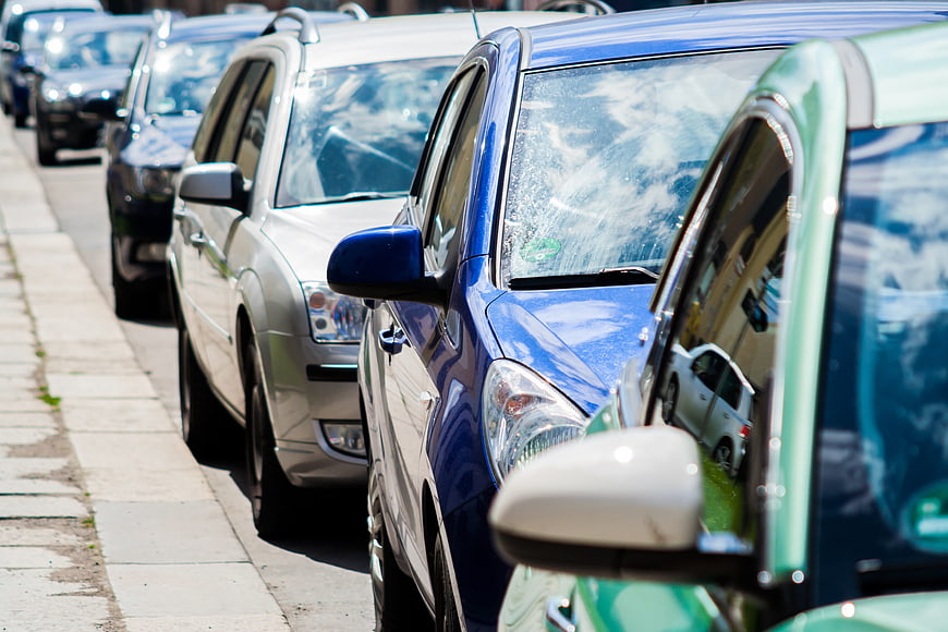 Row of parked cars on a sunny city street