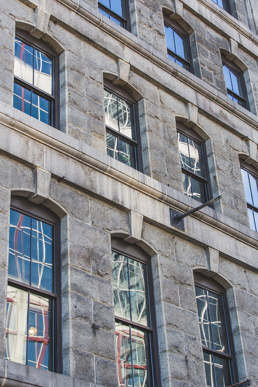 Gray stone building facade with arched windows and reflections
