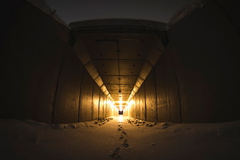 Snowy Concrete Tunnel with Footprints and Warm Light