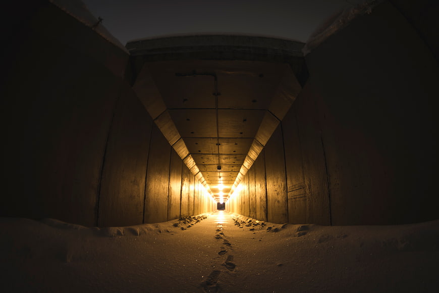 Snowy Concrete Tunnel with Footprints and Warm Light