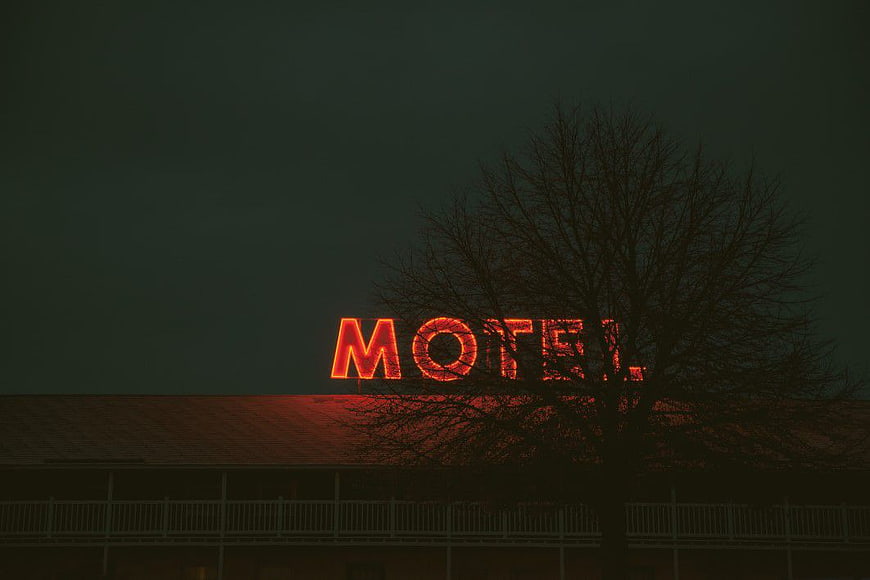 Dark Neon Motel Sign at Night with Silhouette Tree