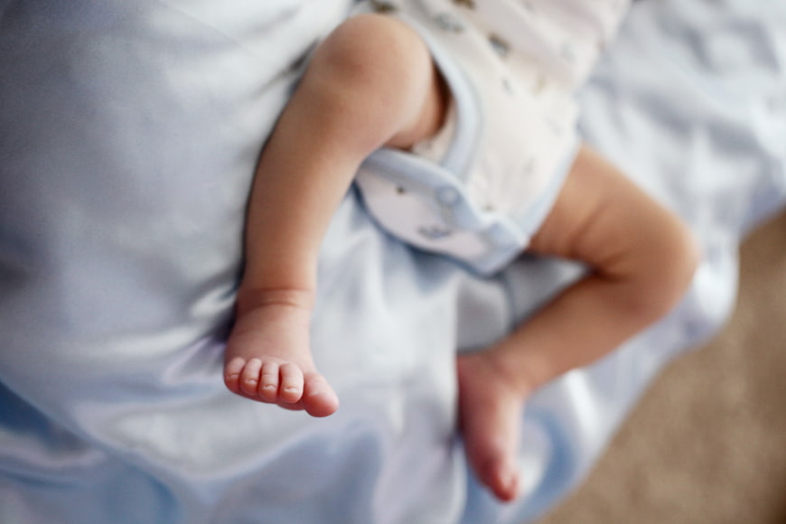 Close-up of baby legs and feet on blue blanket
