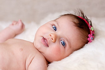 Cute baby girl with blue eyes and pink flower headband