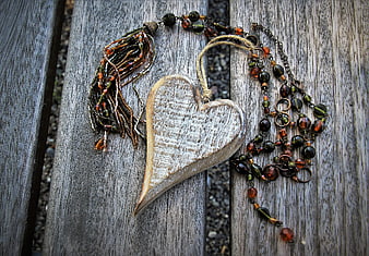 Rustic wooden heart ornament with beaded necklace on weathered gray wood