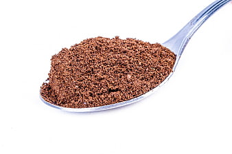 Close-up of brown powder on a silver spoon against a white background