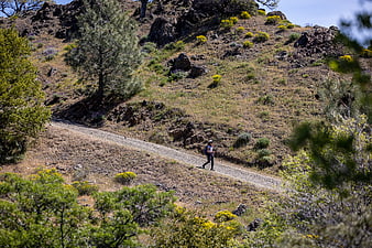 Woman hiking on a dirt path through a rocky mountain landscape
