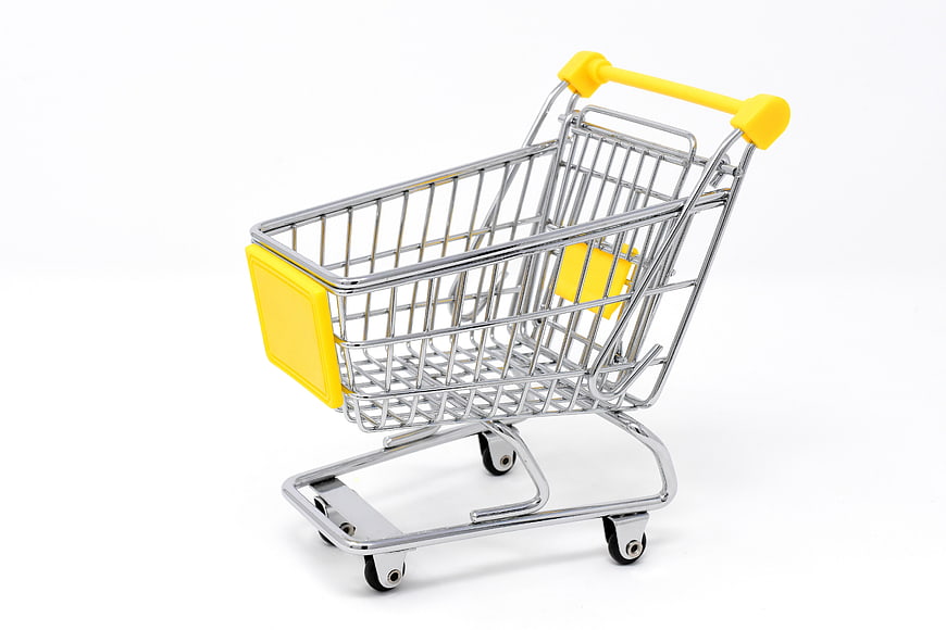Miniature metal shopping cart with yellow handle on white background