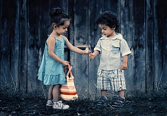 Cute toddler siblings sharing a dandelion outdoors