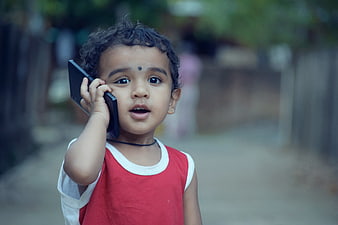 Toddler boy holding smartphone to ear in red shirt