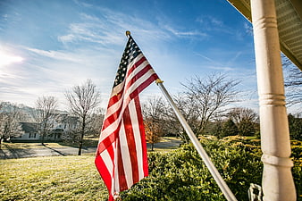 American flag on a residential porch with suburban neighborhood background