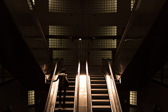 Silhouette of Man on Escalator in Dark Modern Building
