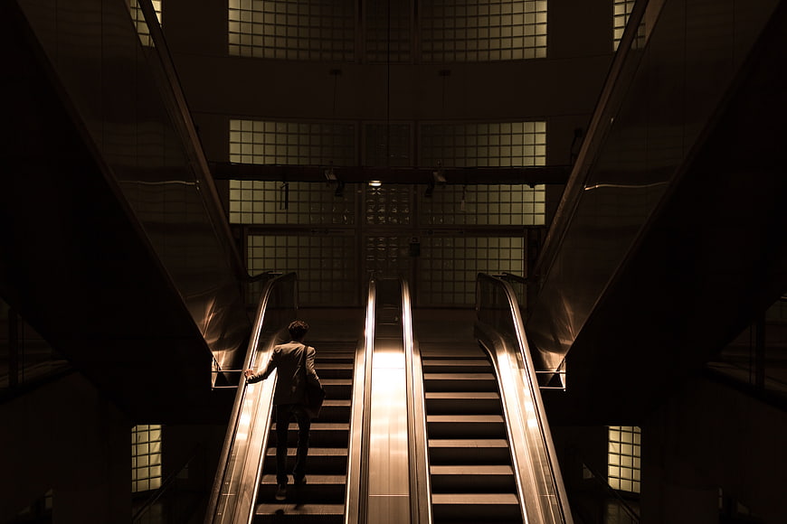 Silhouette of Man on Escalator in Dark Modern Building