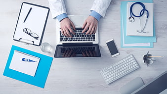 Doctor typing on laptop with stethoscope and medical tools