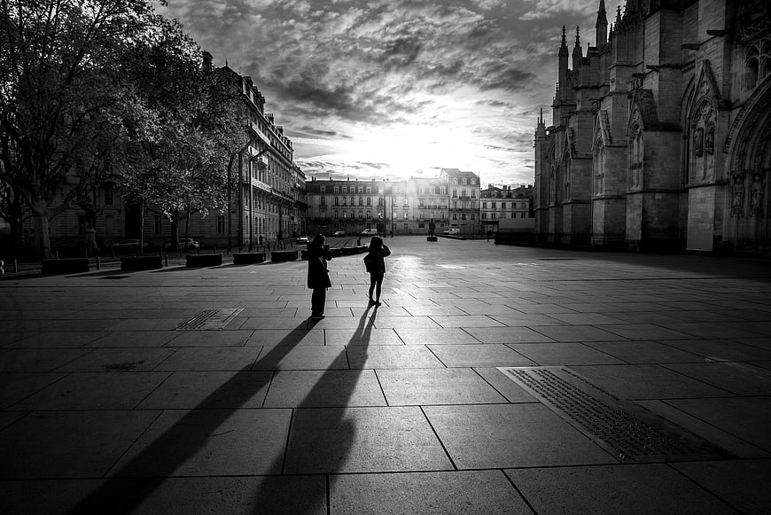 Silhouettes of two people in a European square at sunset
