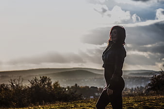 Silhouette of Woman Walking on Hilltop at Sunset