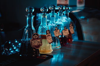Row of glass bottles with handwritten tags on a bar counter
