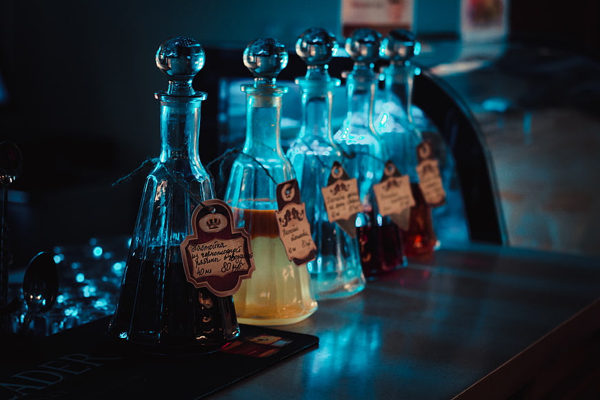 Row of glass bottles with handwritten tags on a bar counter