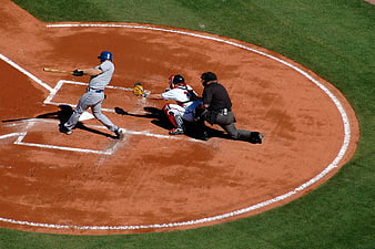 Baseball batter swinging at home plate with catcher and umpire