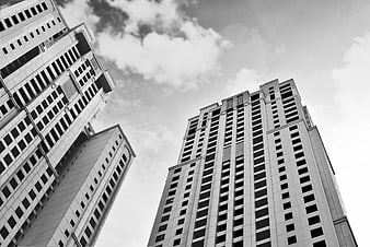 Black and white low angle view of modern skyscrapers against cloudy sky