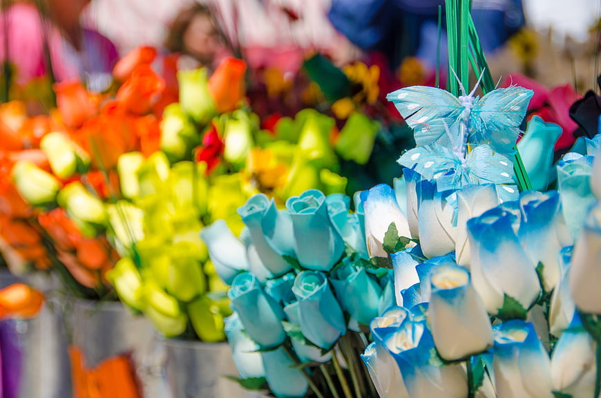 Colorful dyed roses and artificial butterflies at flower market