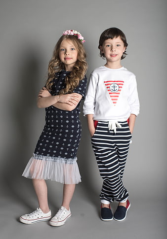 Two children modeling nautical fashion on gray background