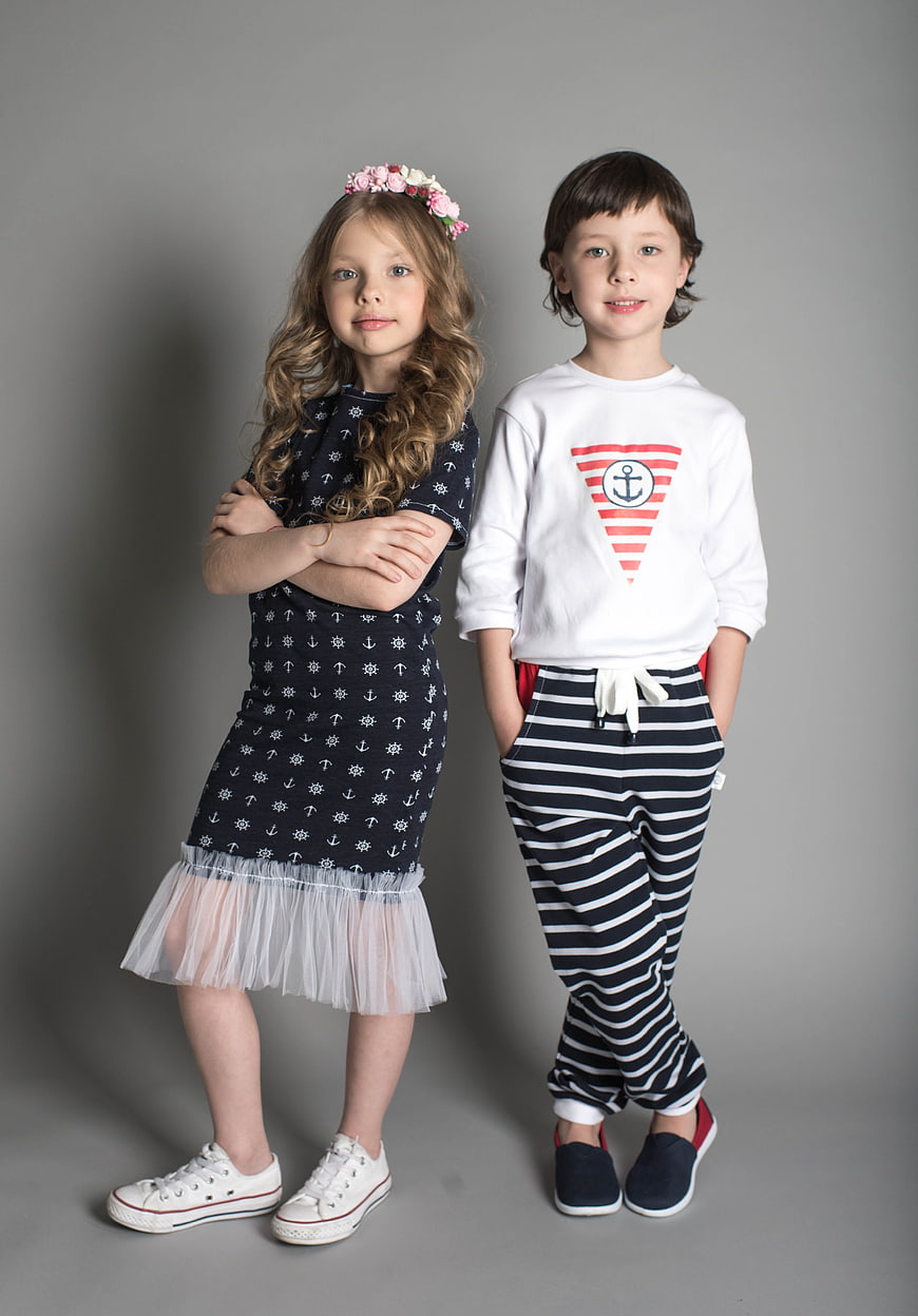 Two children modeling nautical fashion on gray background