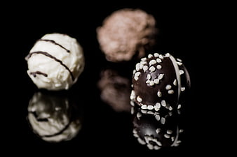 Gourmet chocolate truffles on black reflective surface