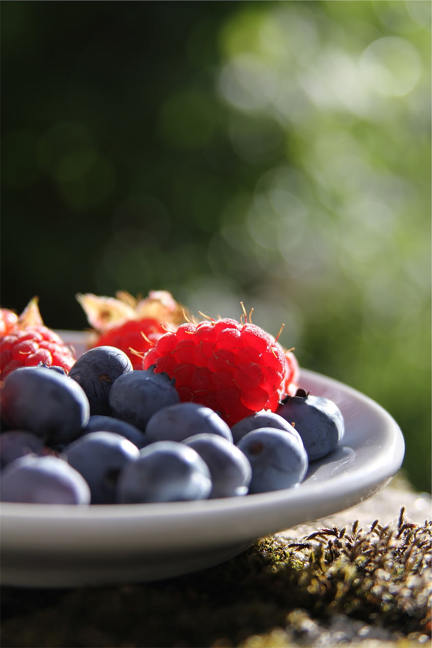 Fresh Raspberries and Blueberries on a White Plate Outdoors