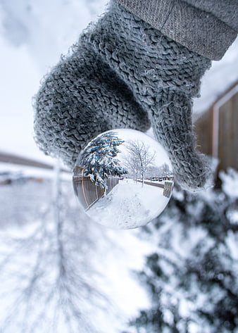 Hand holding crystal ball reflecting snowy winter street