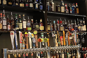 Well-stocked bar shelves with liquor bottles and beer taps