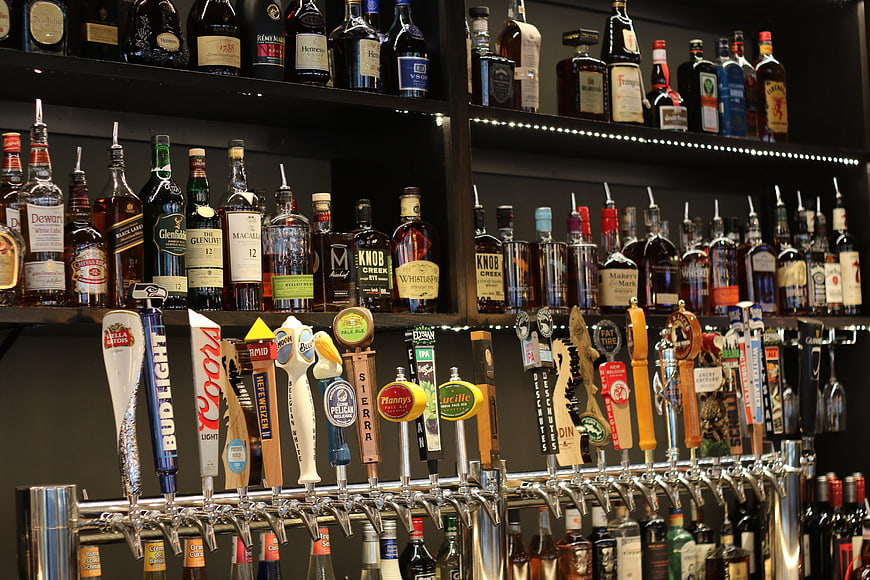 Well-stocked bar shelves with liquor bottles and beer taps