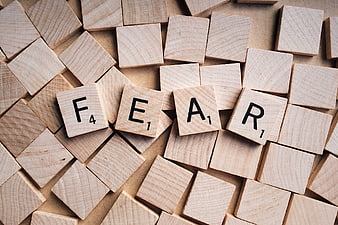 Wooden Scrabble Tiles Spelling Fear on Scattered Background