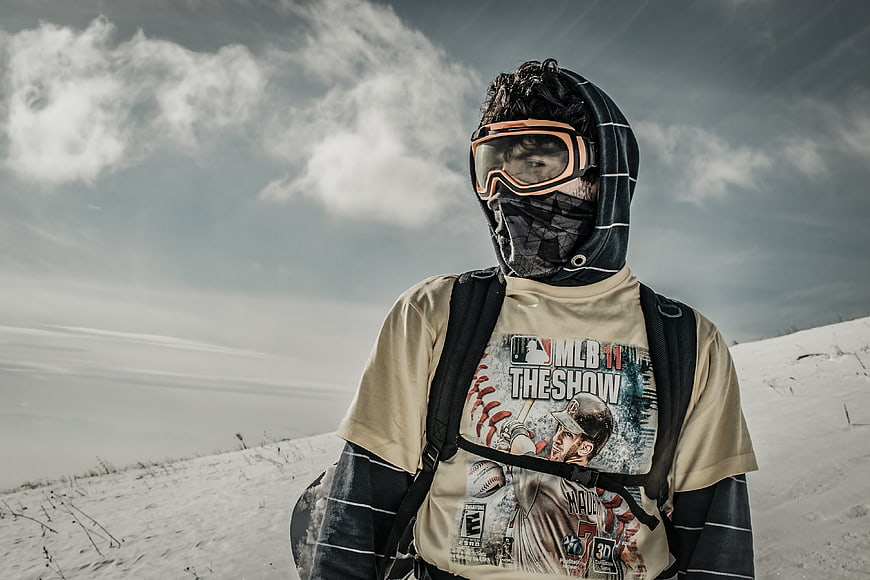 Snowboarder in winter gear standing on snowy mountain slope