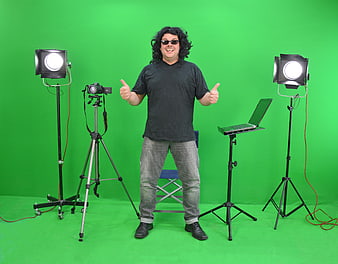 Man giving thumbs up in a green screen studio with camera and lights