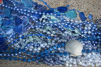 Blue glass beads and seashell on sand texture
