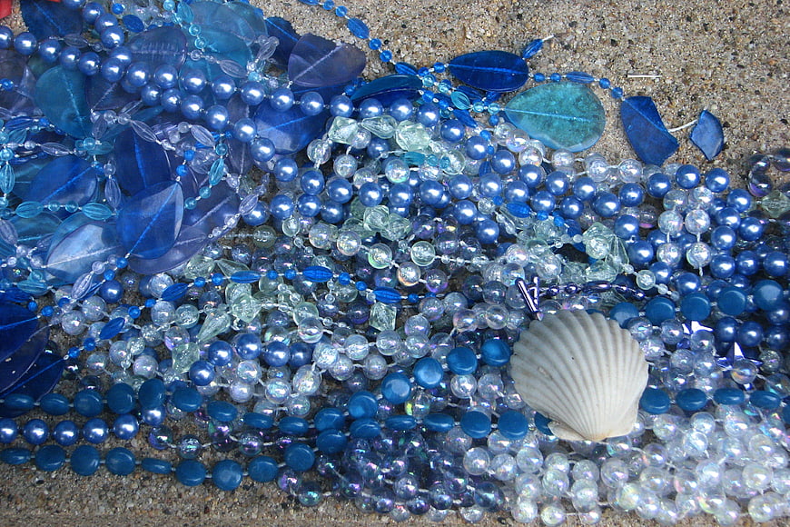Blue glass beads and seashell on sand texture