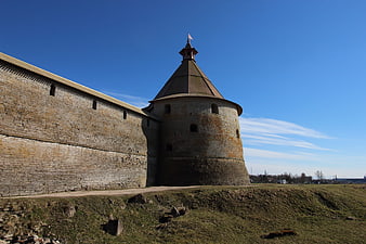 Historic stone fortress tower and wall against blue sky