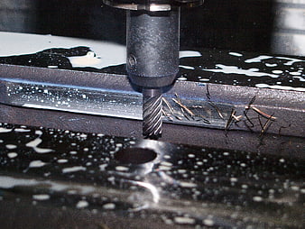 Close-up of CNC milling machine cutting metal with coolant spray