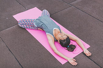Woman relaxing on pink yoga mat outdoors