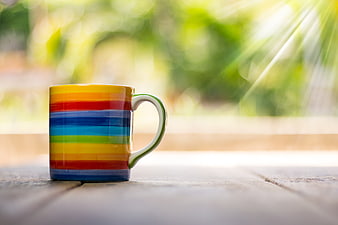 Colorful Rainbow Striped Mug on Wooden Table with Sunlight