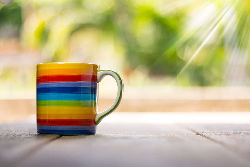 Colorful Rainbow Striped Mug on Wooden Table with Sunlight