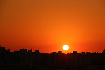 Vibrant orange sunset over a silhouetted city skyline
