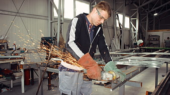 Male Worker Grinding Metal with Angle Grinder in Workshop