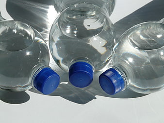 Three Clear Plastic Water Bottles With Blue Caps On White Surface